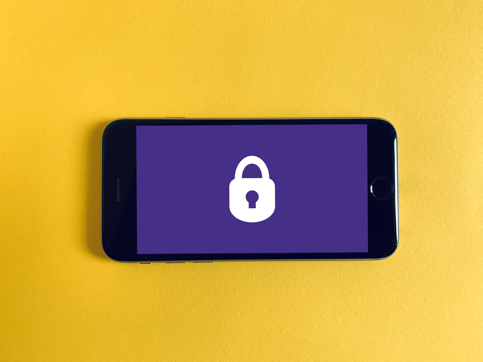Een telefoon met een slotje op het scherm, op een gele achtergrond